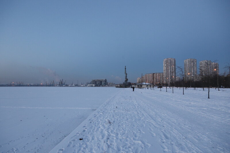 Snowy riverbank with city skyline