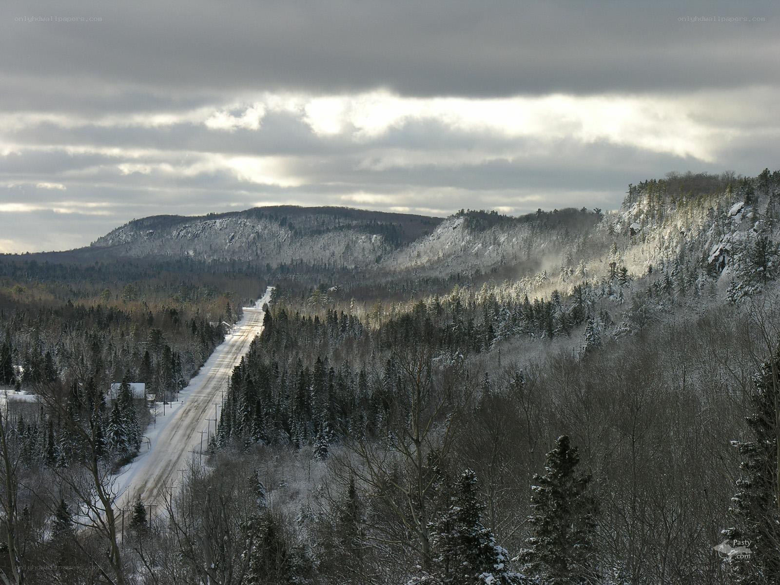 Snowy road through forested hills