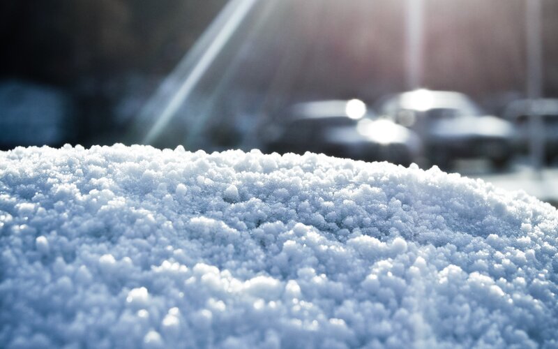 snowy surface with cars in background