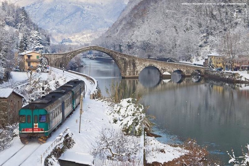 Snowy train crossing stone bridge