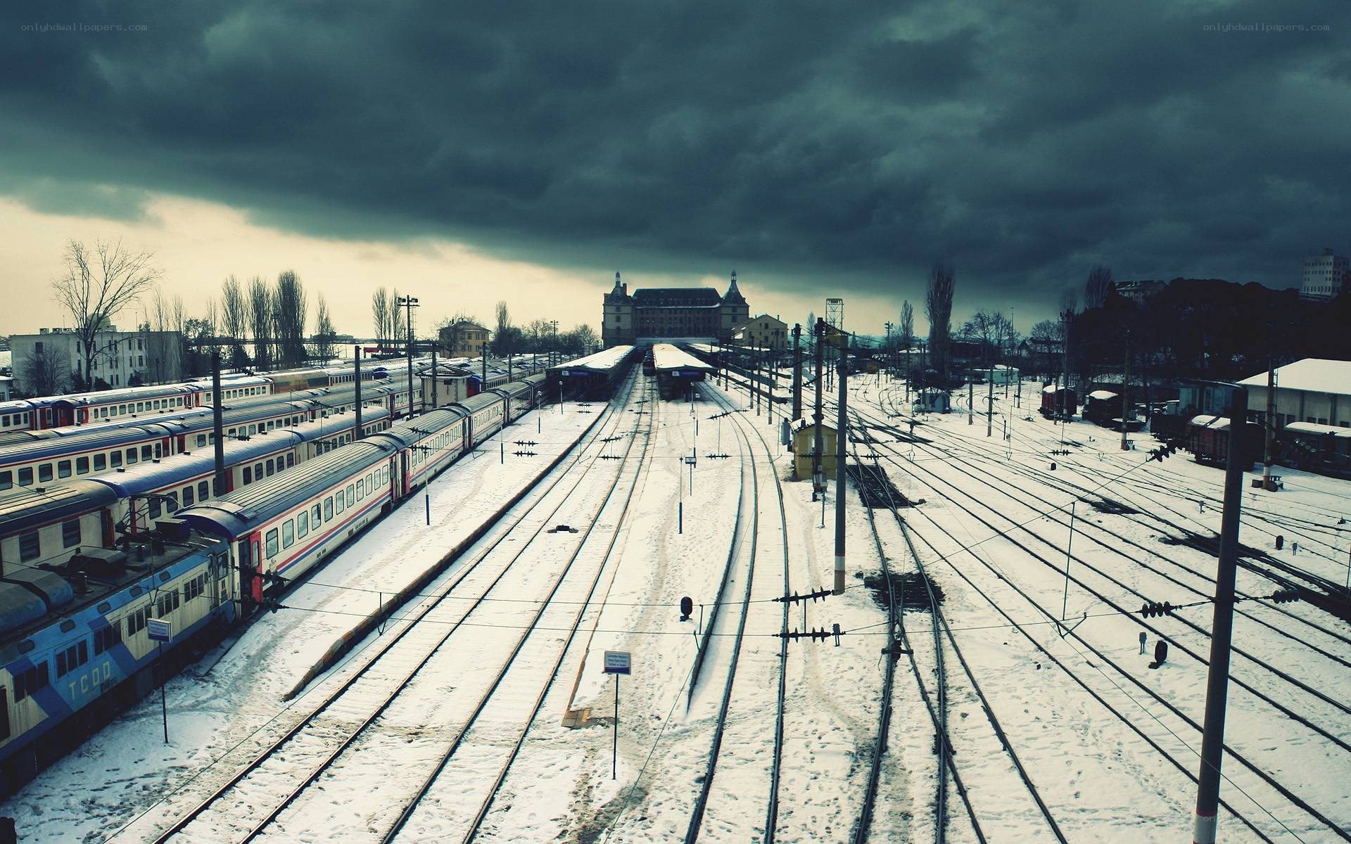 Snowy train yard under stormy sky