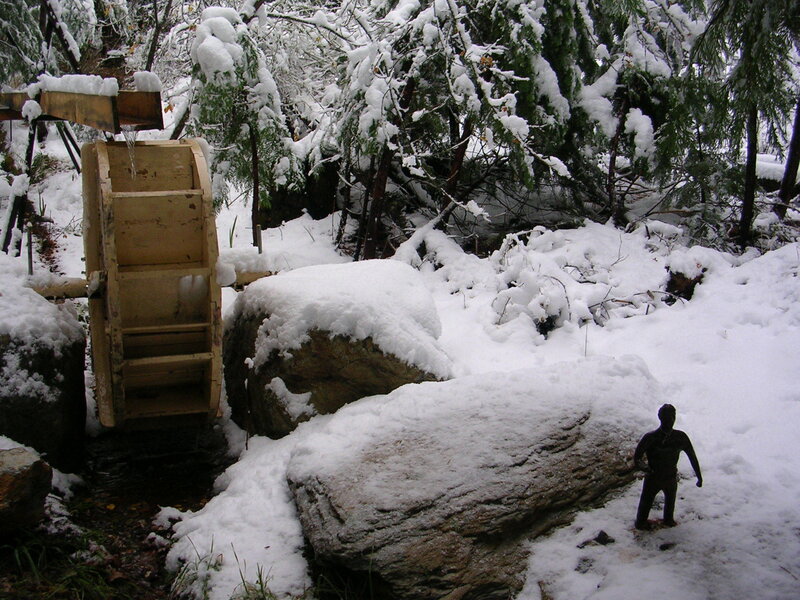 Snowy waterwheel in forest