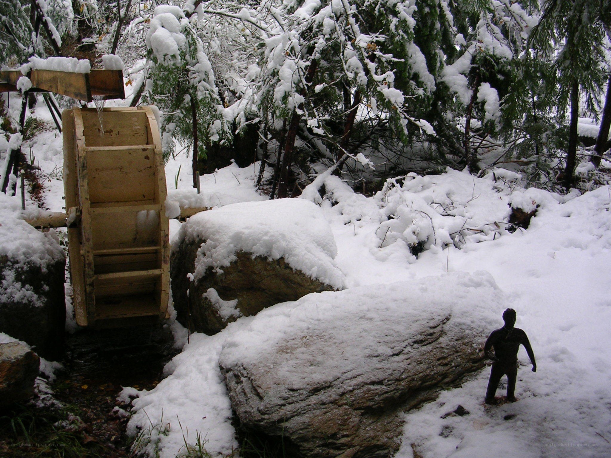 Snowy waterwheel in forest