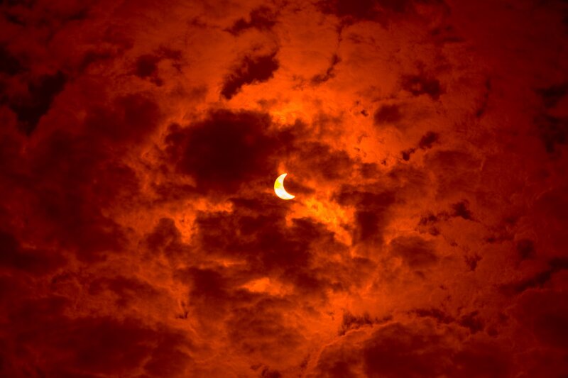 Solar Eclipse in Clouds — Red