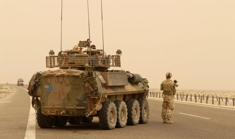 Soldier and armored vehicle on desert road