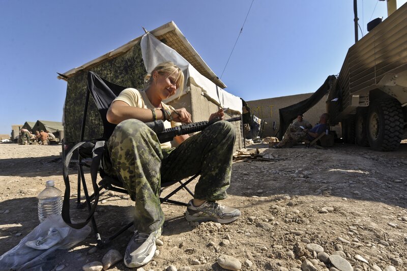 Soldier cleaning rifle in camp