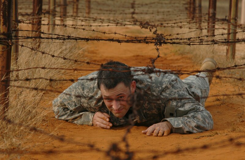 Soldier crawling under barbed wire