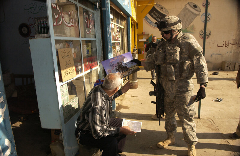 Soldier distributing leaflets to a man