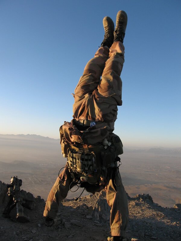 Soldier doing handstand on mountain