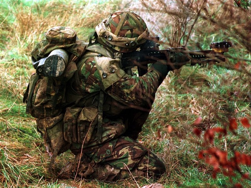 Soldier in camouflage aiming rifle