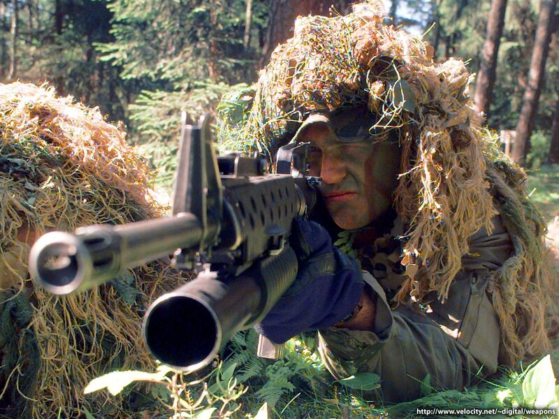soldier in ghillie suit aiming rifle