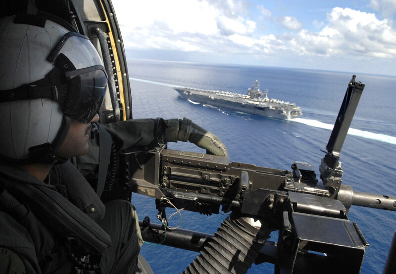 Soldier in helicopter with aircraft carrier