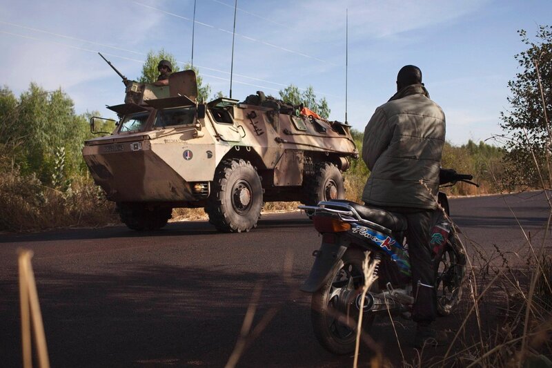 Soldier on motorcycle near armored vehicle