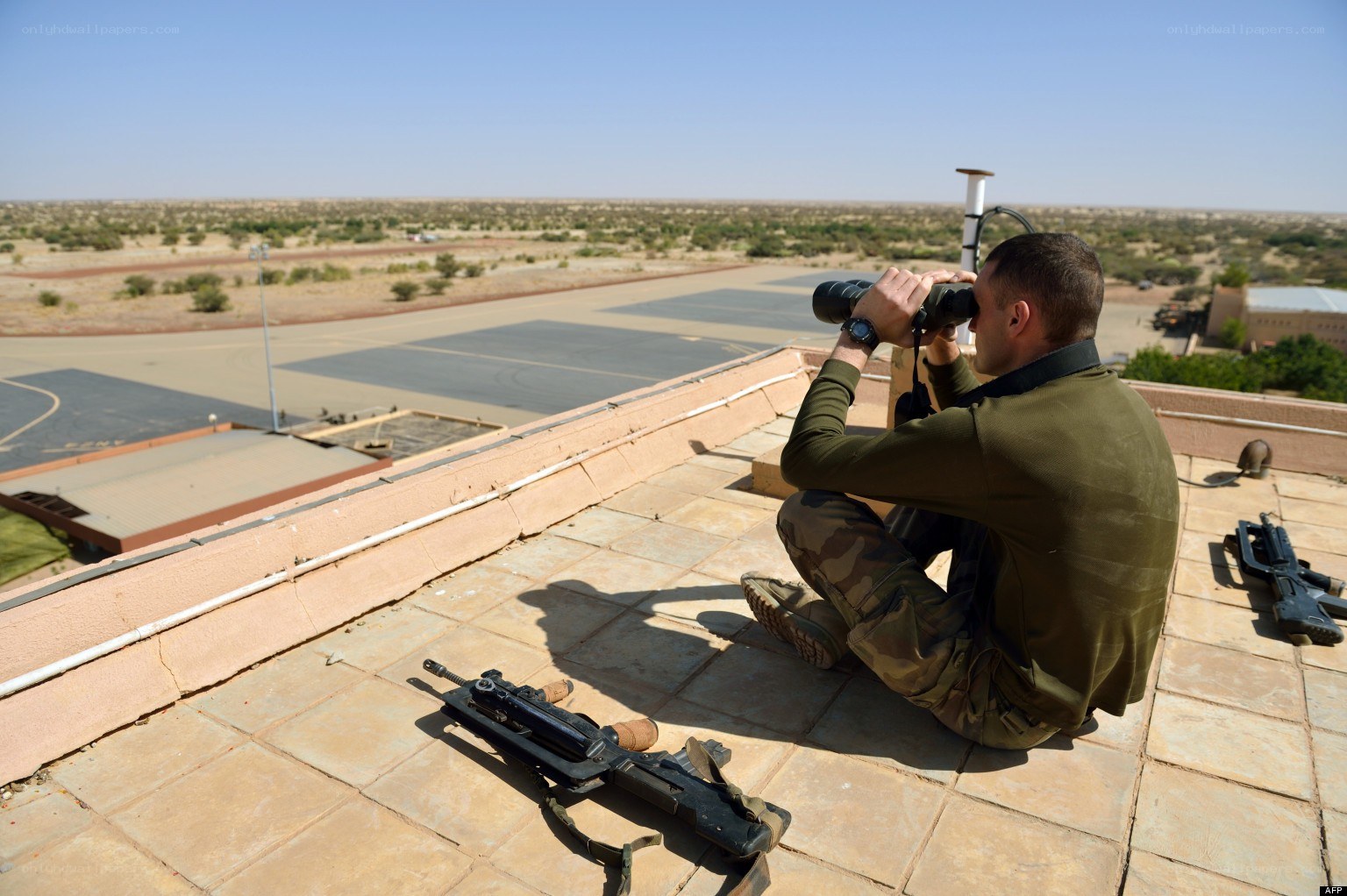 Soldier on rooftop with binoculars