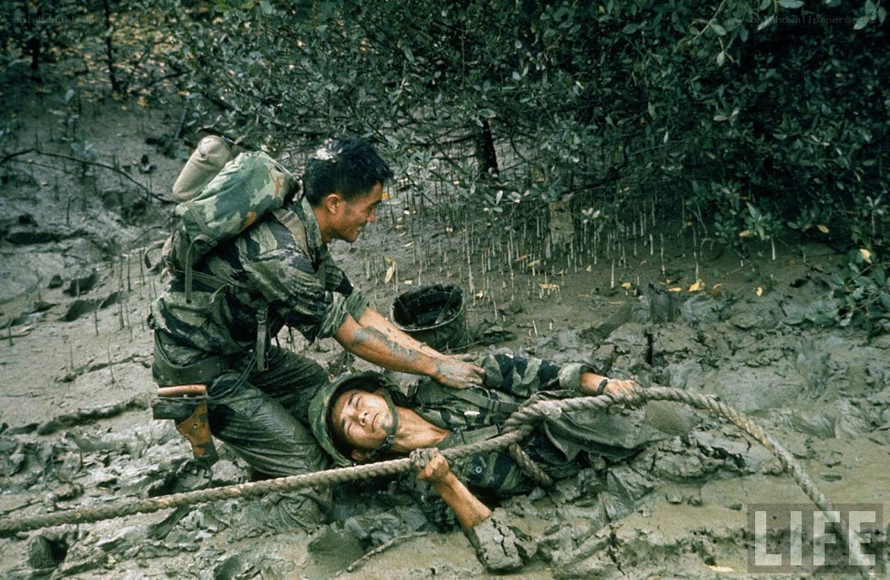 Soldier rescuing comrade in mud
