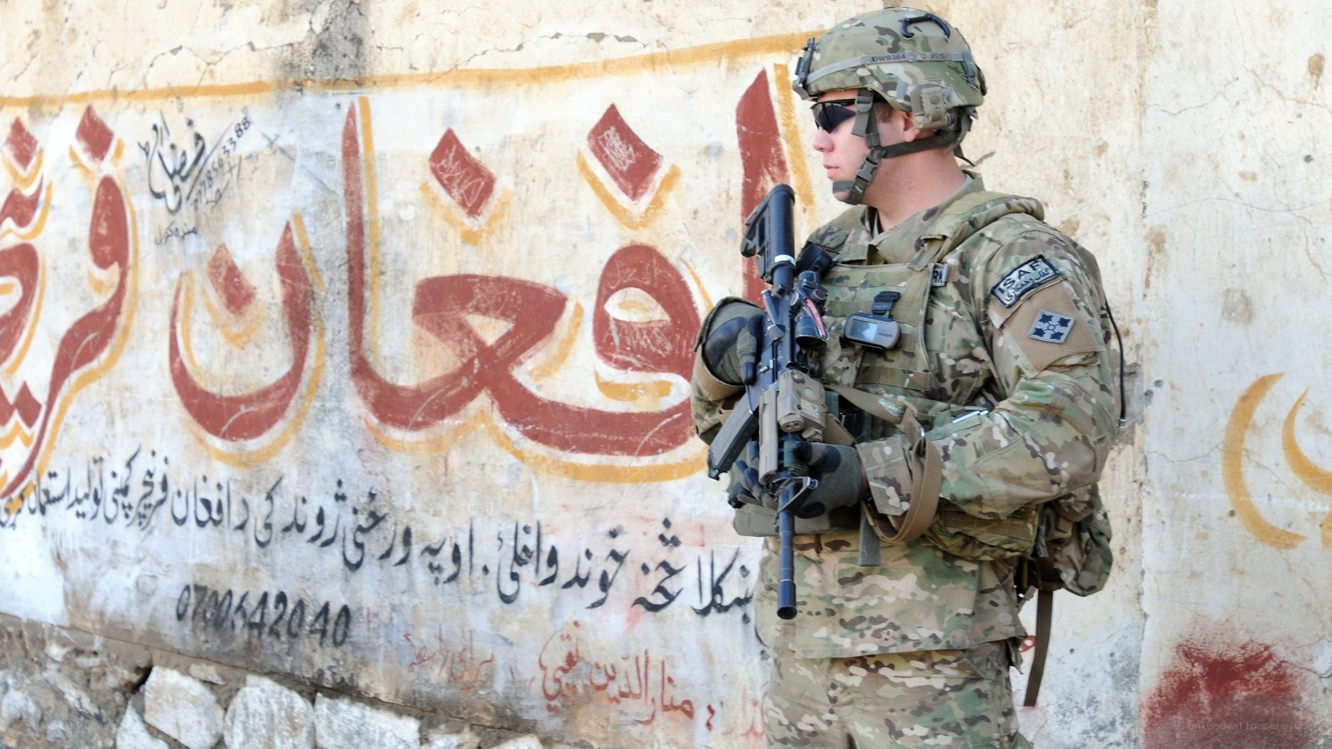 Soldier standing guard near graffiti