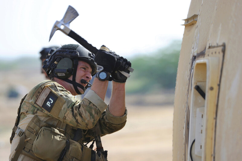 Soldier using axe on vehicle