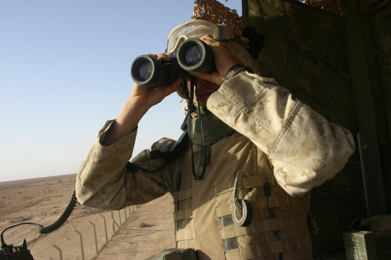 Soldier using binoculars in desert