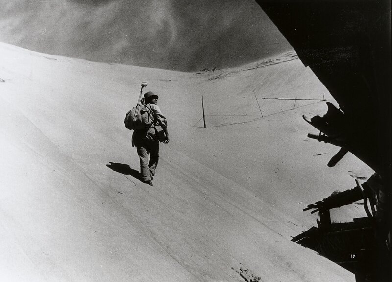Soldier walking on sand dune