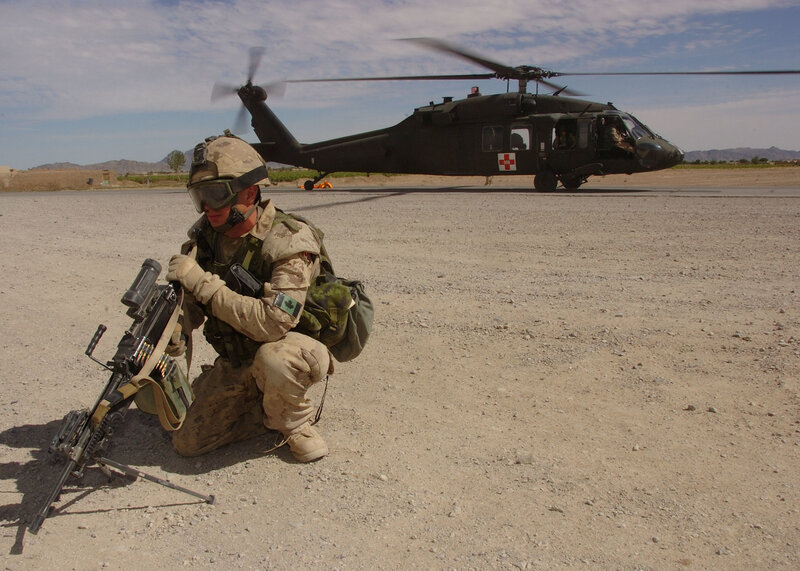 Soldier with machine gun near helicopter