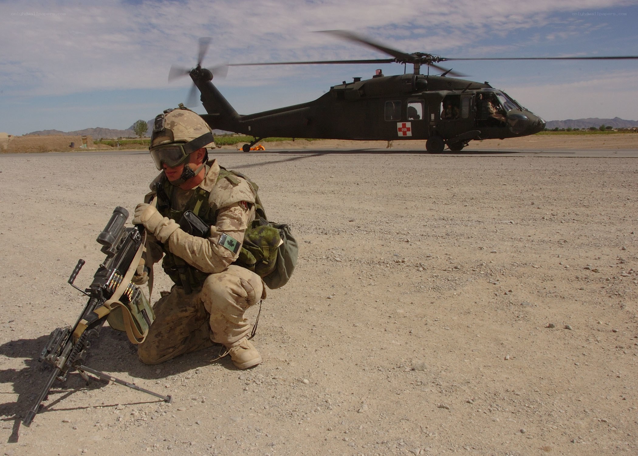 Soldier with machine gun near helicopter