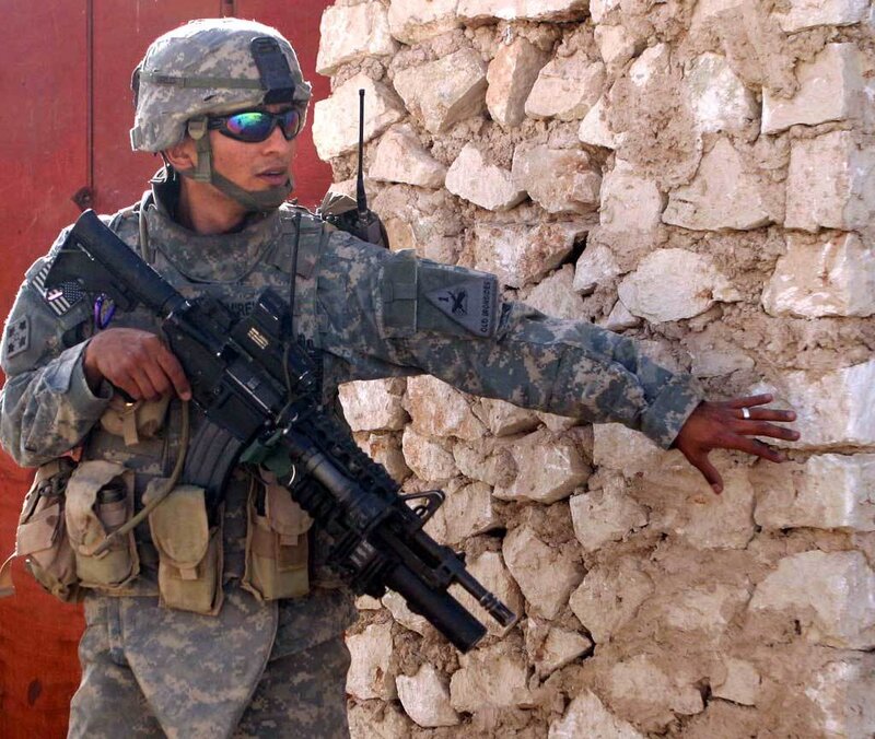 Soldier with rifle near stone wall