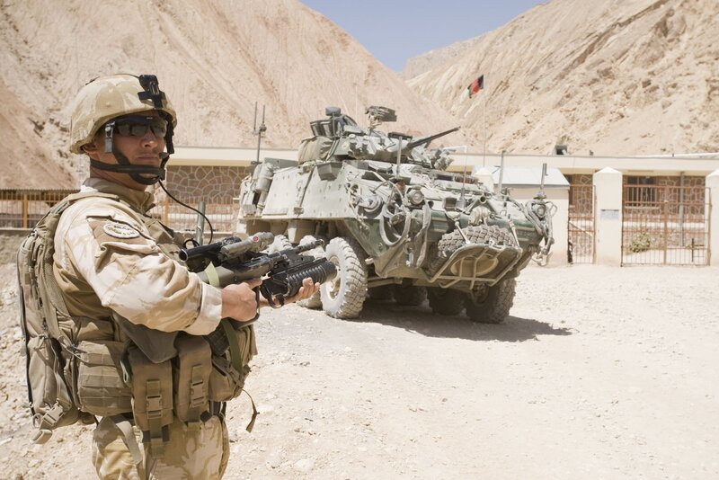 Soldier with Rifle — Tan, Alert, Afternoon, Photograph, Armored Vehicle, Mountain, Building