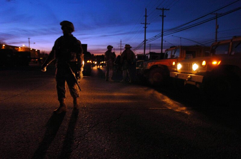 Soldiers at dusk with military vehicles