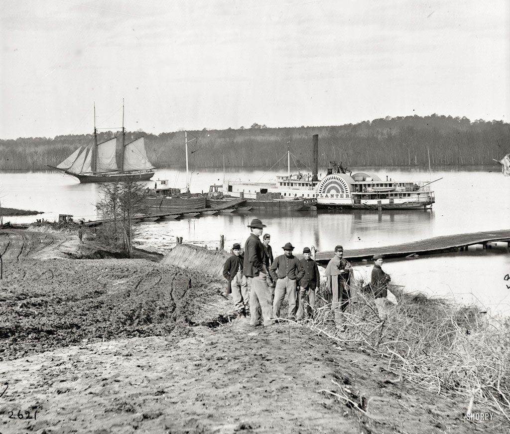 Soldiers by river with steamboat