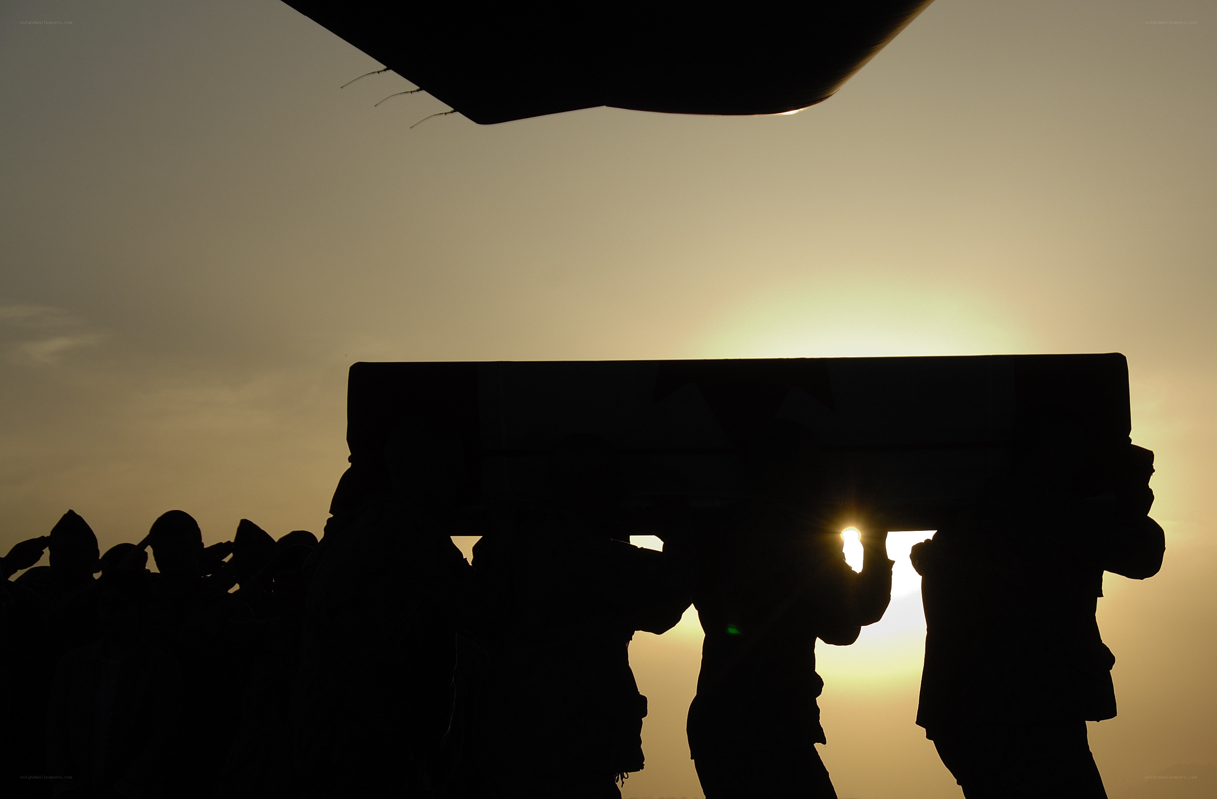 Soldiers carrying a coffin at sunset