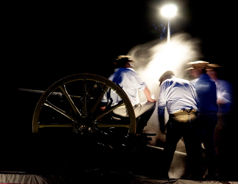 Soldiers firing cannon at night