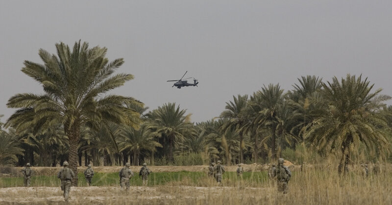 Soldiers in palm grove with helicopter