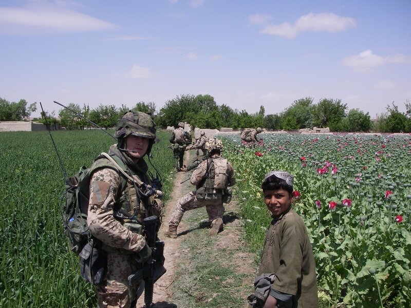 Soldiers in poppy field with child