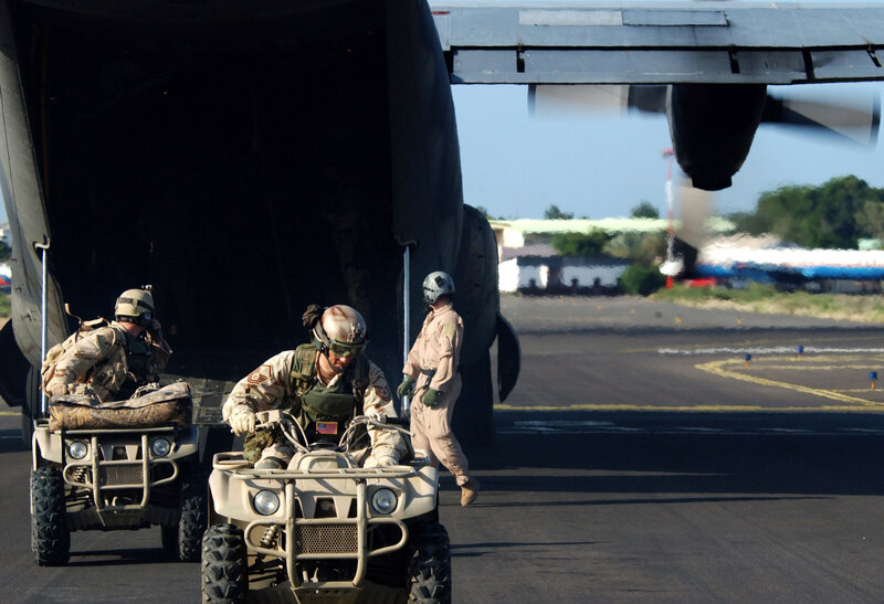Soldiers loading ATVs into a cargo plane