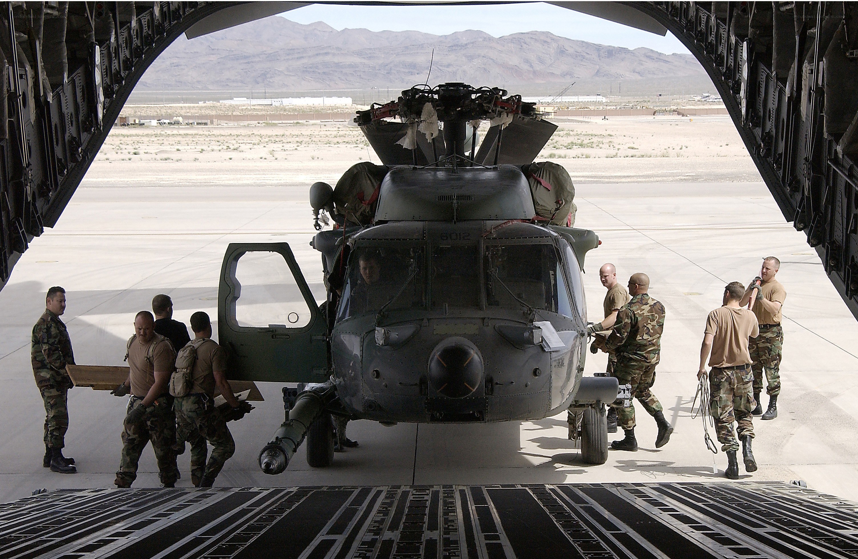 Soldiers loading helicopter into cargo plane