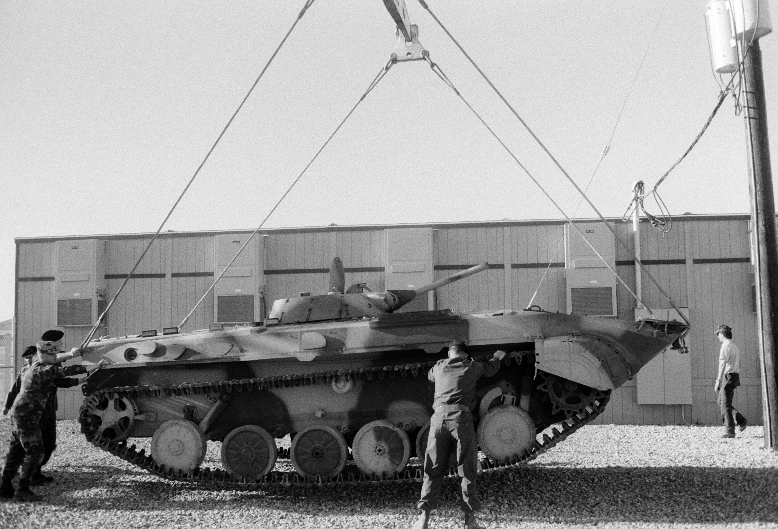 Soldiers loading tank onto crane