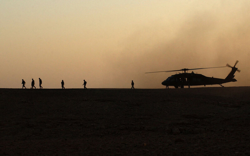 Soldiers near helicopter at dusk