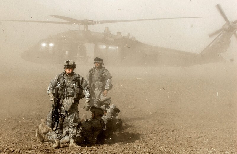 Soldiers near helicopter in dust