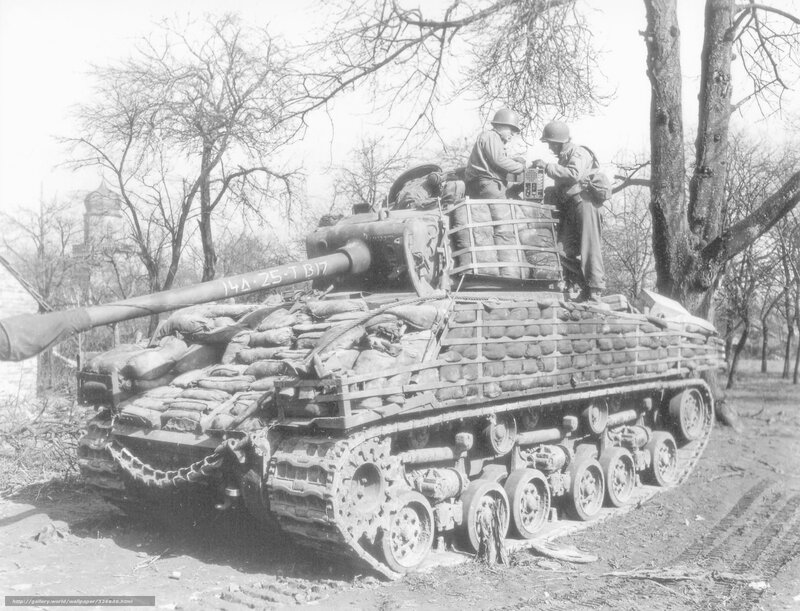 Soldiers on a tank in a wooded area