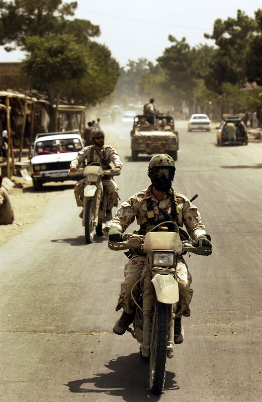 Soldiers on motorcycles in a dusty town