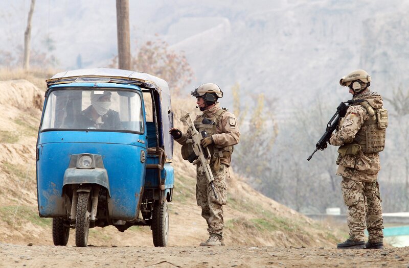 Soldiers stop a blue auto-rickshaw