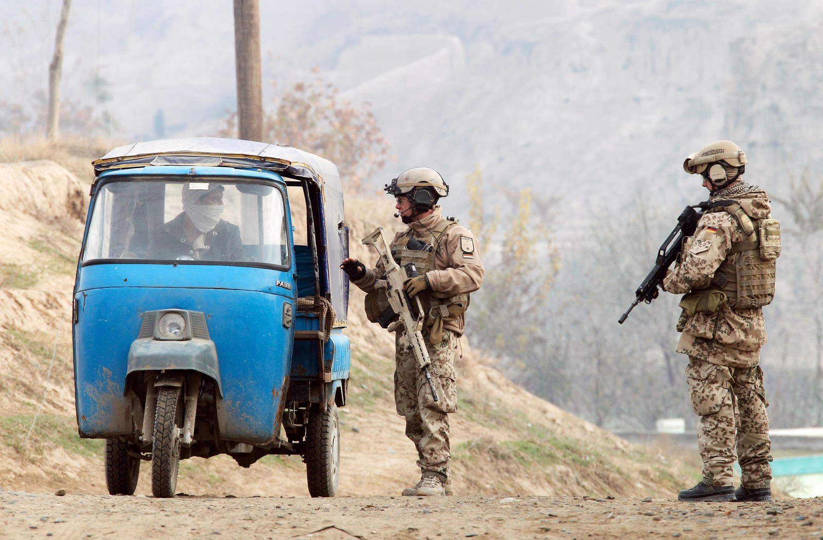 Soldiers stop a blue auto-rickshaw