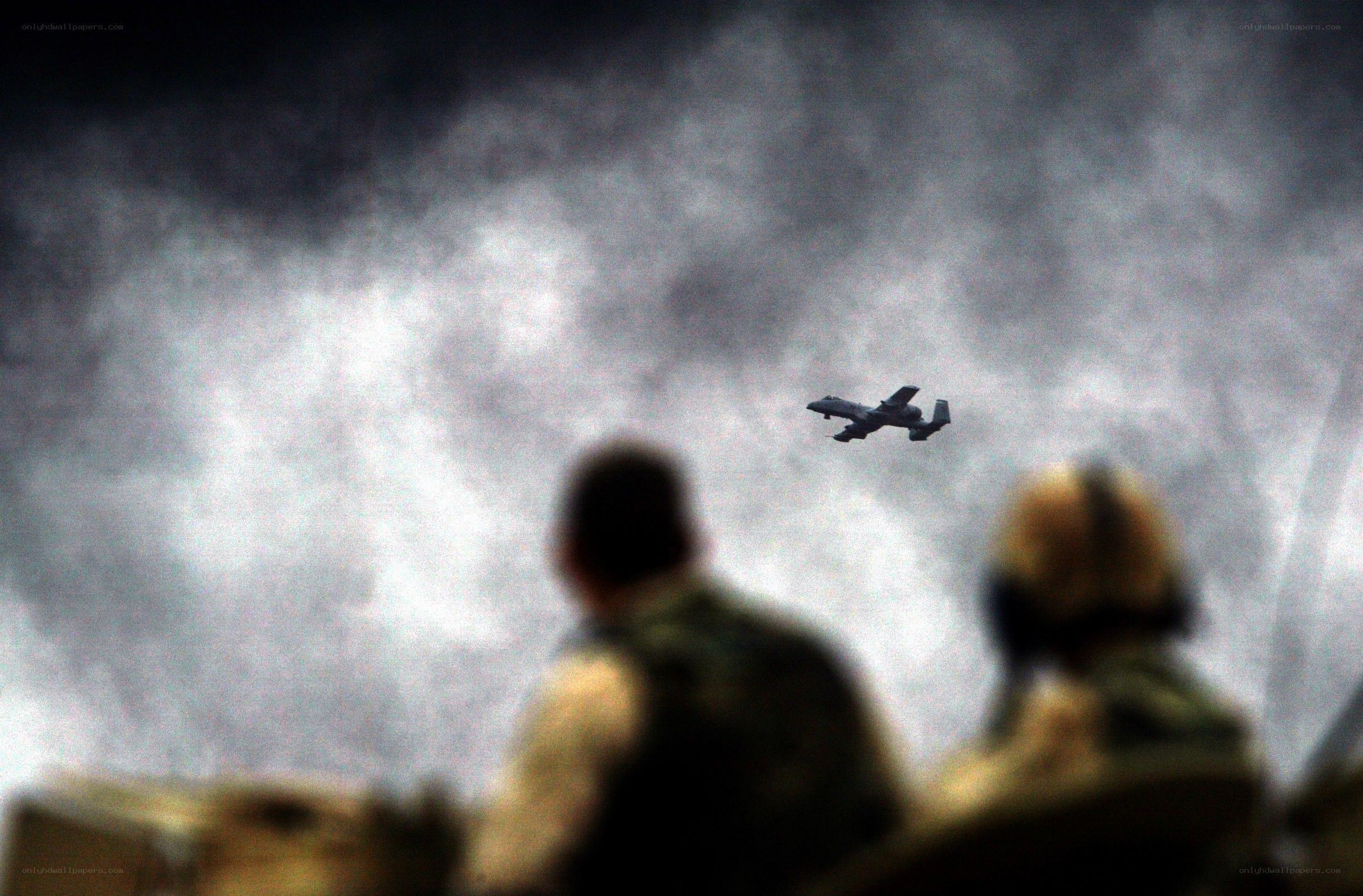 Soldiers watch aircraft fly overhead