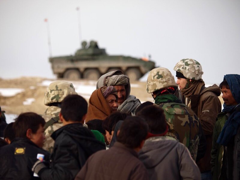 Soldiers with civilians near armored vehicle