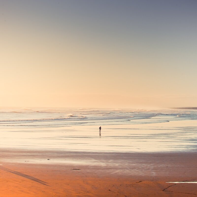Solitary figure on beach at sunset