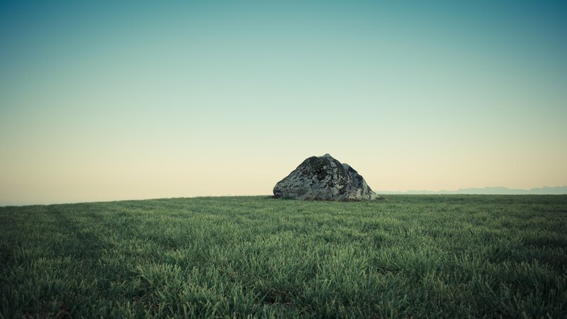 solitary rock in a green field