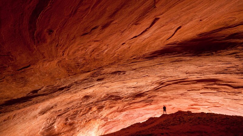 Solo hiker in red rock cave