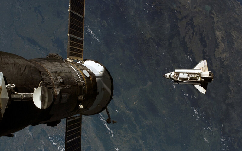 Space shuttle and satellite in orbit