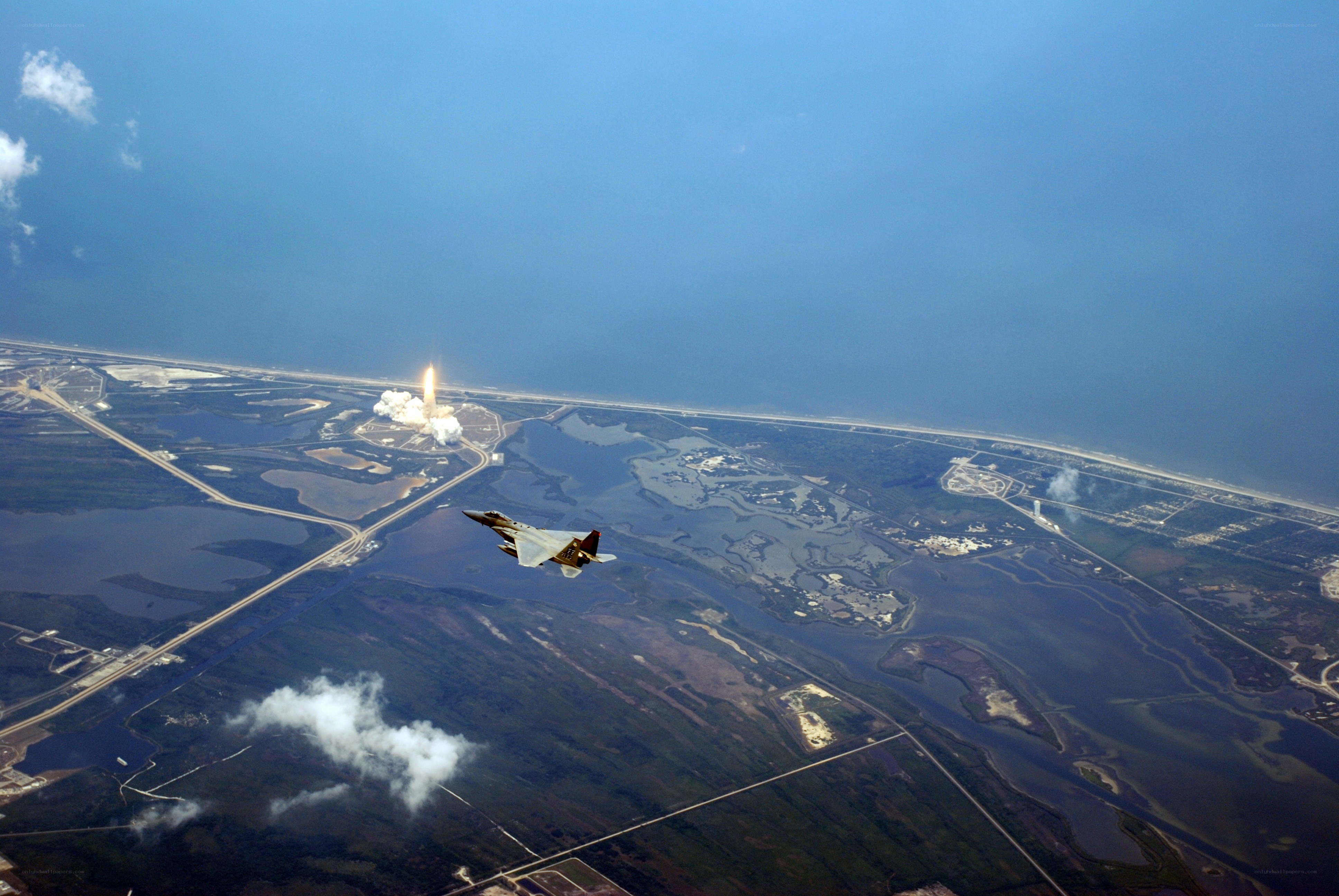 Space shuttle launch with fighter jet
