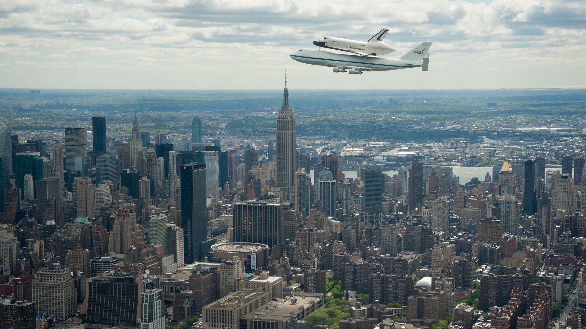 Space shuttle on carrier plane over city